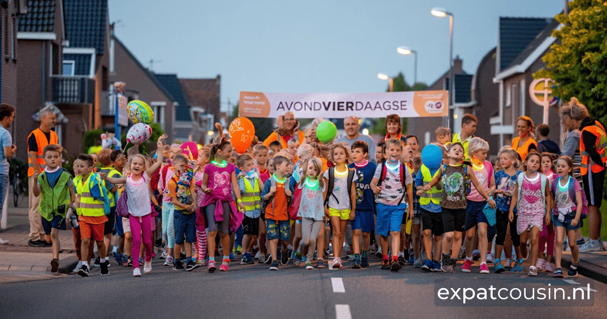 A group of children and adults walking down the street in front of houses.