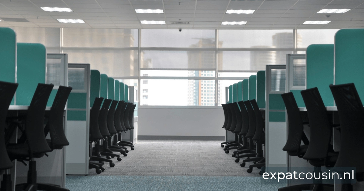 An empty office with black chairs and green cubicle seperation walls.